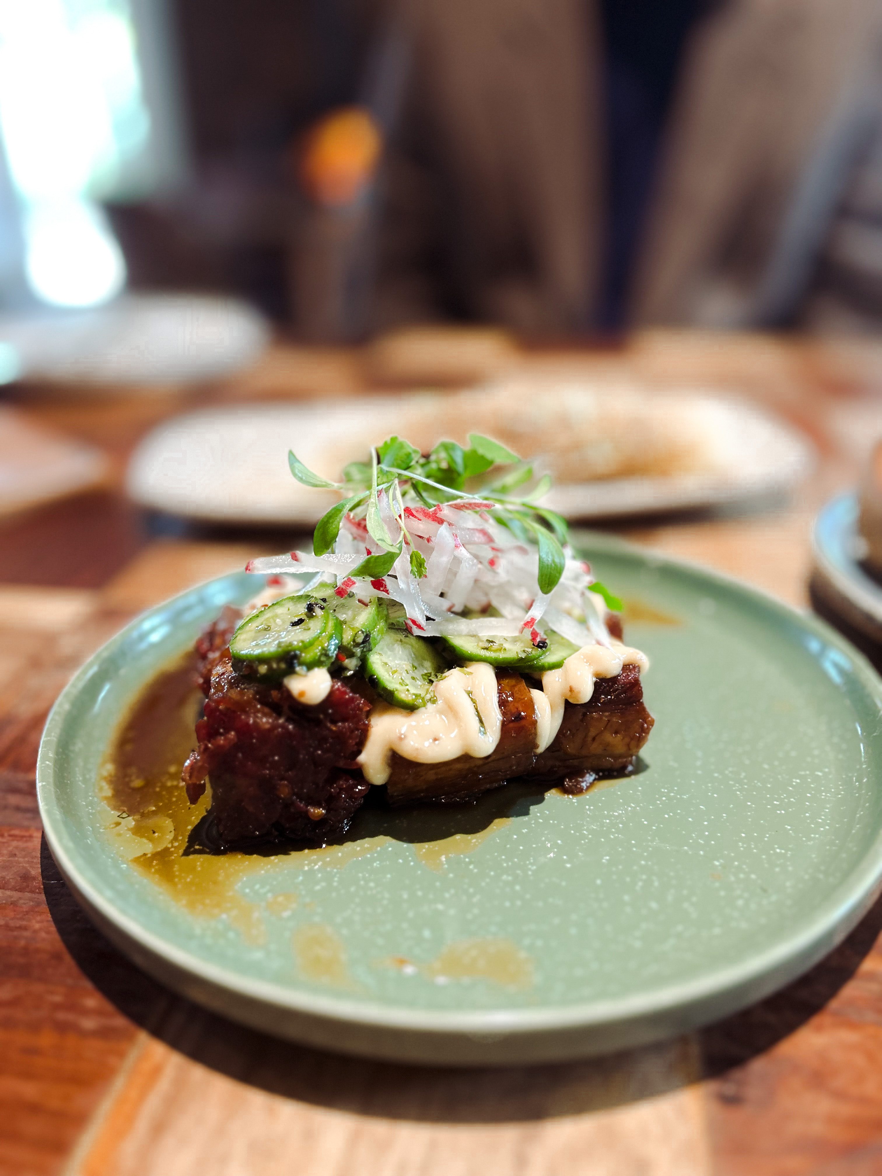 A close-up of the mouthwatering Pork Belly dish, beautifully presented with crispy skin and succulent meat, served at Pink Valley Wine Farm.