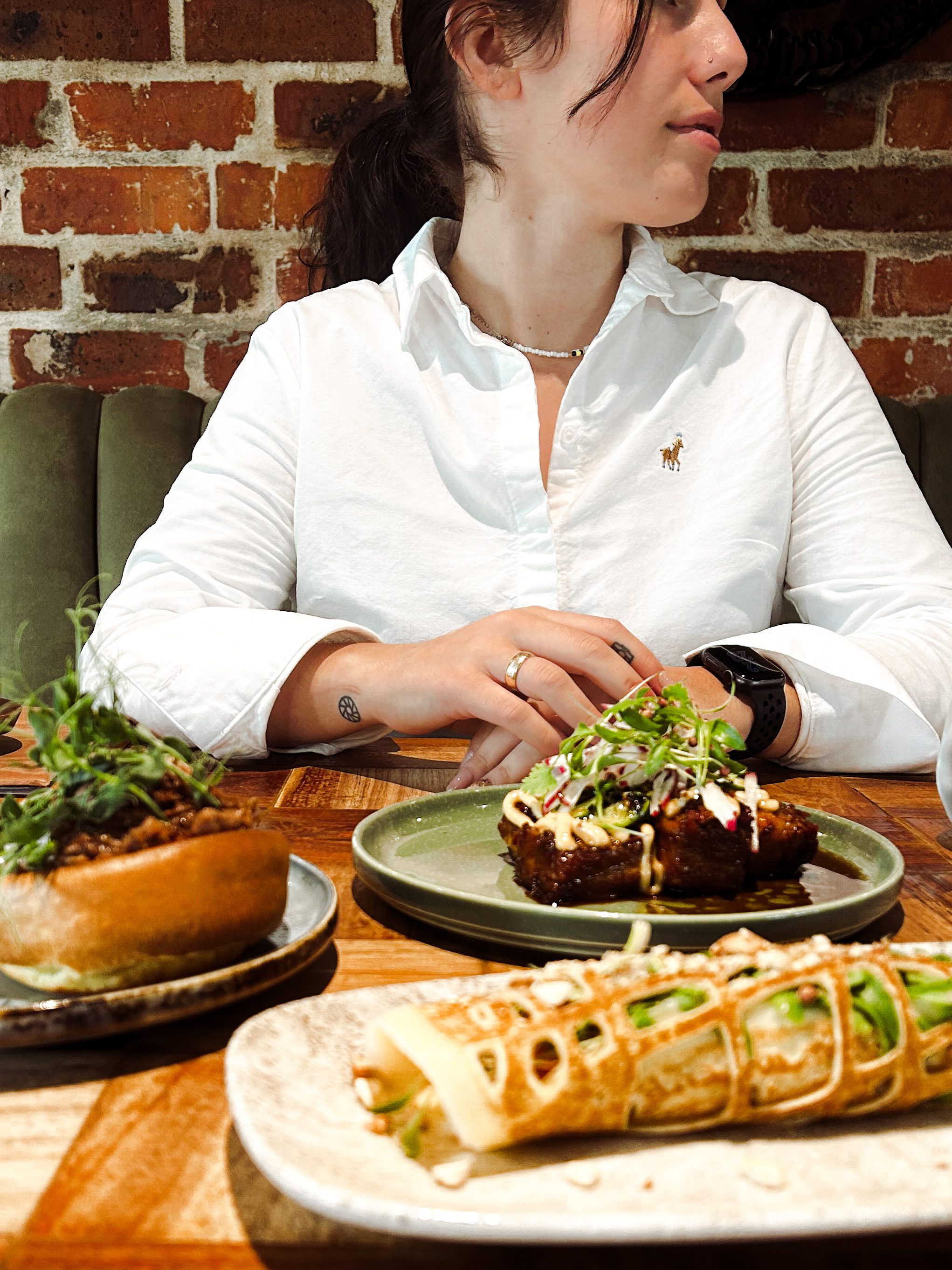 Jessica happily sitting behind a sumptuous spread of delectable dishes at Pink Valley Wine Farm, ready to enjoy a delightful meal with a big smile on her face.